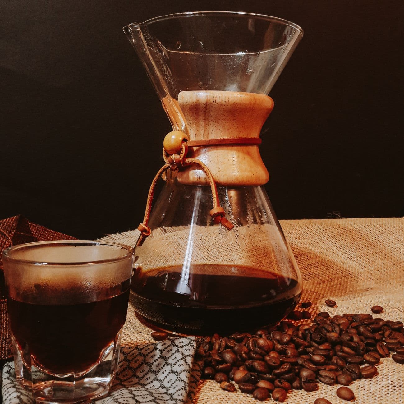 Chemex 手沖壺與一杯黑咖啡,旁邊散落咖啡豆